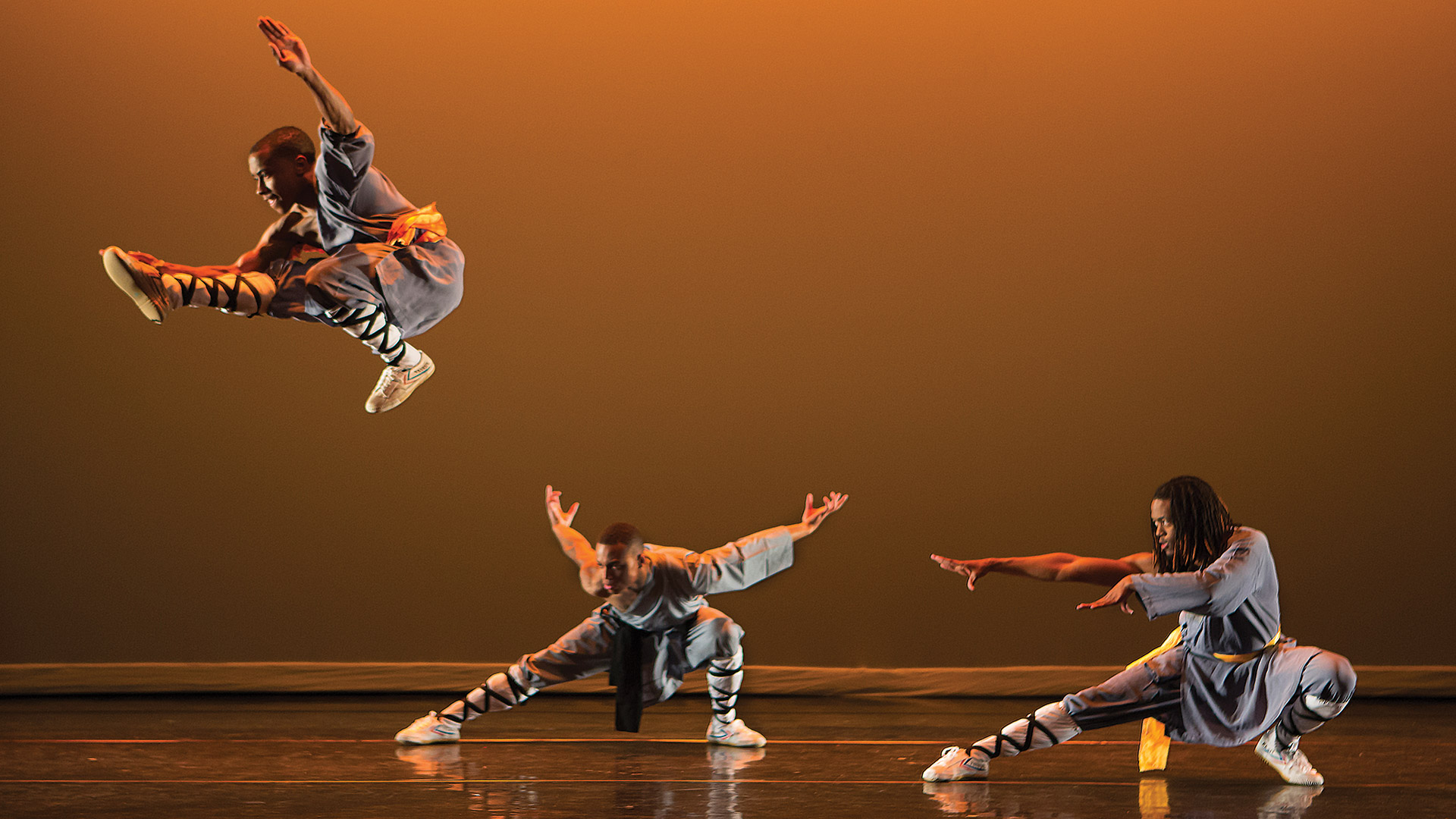 Three male dancers with one leaping high into the air.